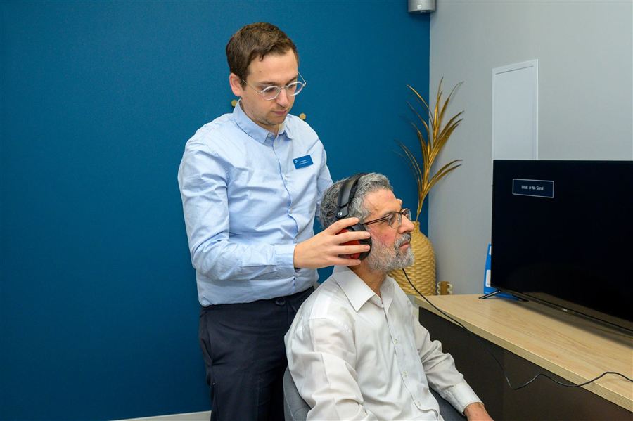 Bilan auditif chez Audistra à Strasbourg : un audioprothésiste place un casque d'audiométrie à un patient